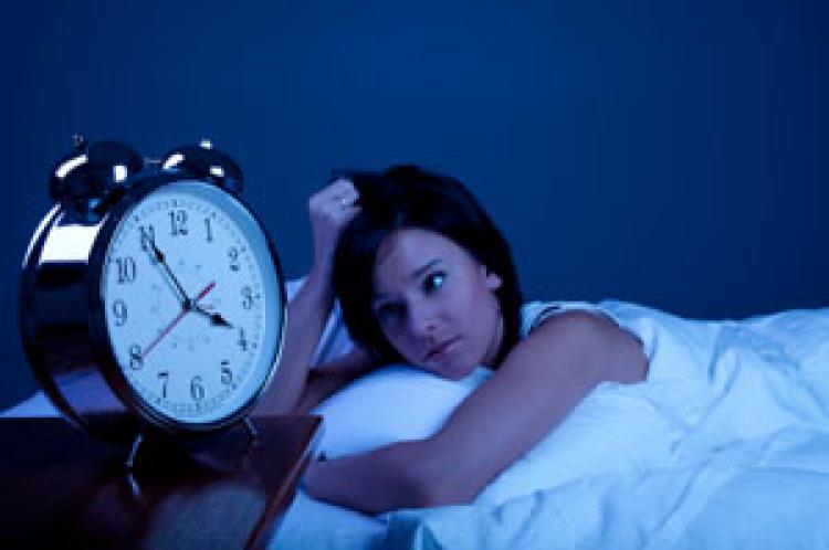 Girl in bed staring at alarm clock