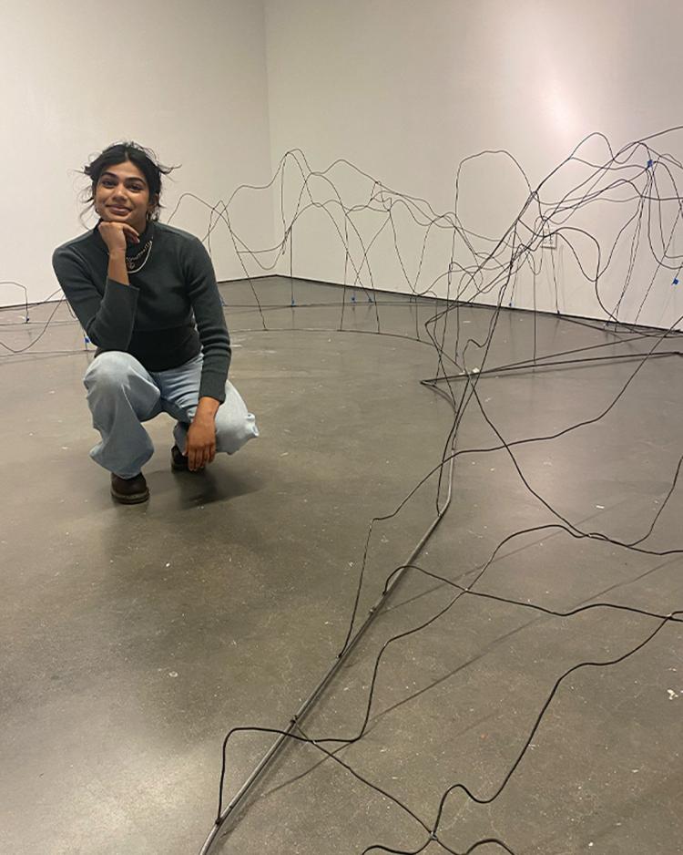 Shloka Dhar posing next to the framework of her thesis project.