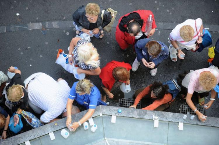 Pilgrims filling bottles with spring water flowing from taps installed near the grotto of the Sanctuaries of Lourdes in 2008. Eric Cabanis/ AFP via Getty Images
