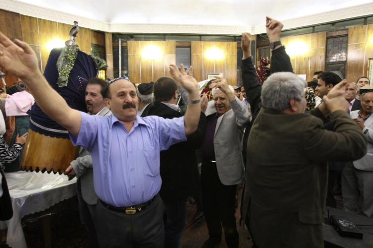 Jewish men in Tehran, Iran, dance during Simchat Torah as one holds the covered Torah scroll