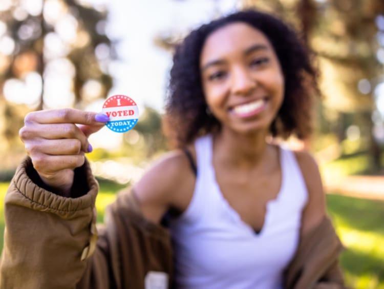 Young woman holding an I Voted sticker