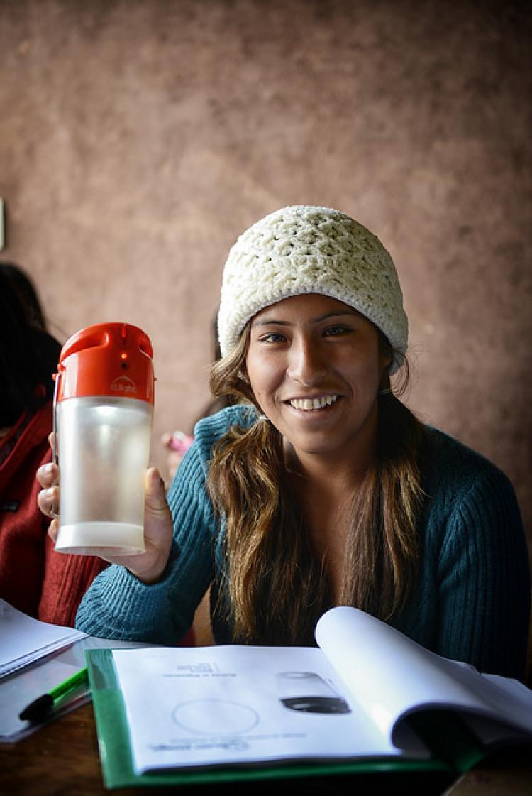 A young Peruvian woman shows off a solar-powered light, which can help residents see and read at night. Photo by Chris Carruth.