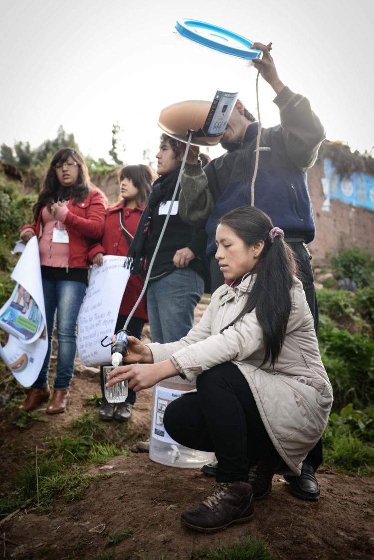 Katheryne Rosa Barazorda Cuellar, kneeling, demonstrates a water filter that rural Peruvians can use to get safe, affordable drinking water.