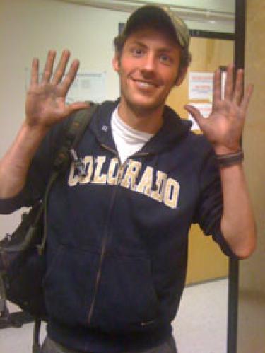 Joseph Knelman, undergraduate in ecology and environmental biology, shows off his soot-stained hands, which reflect his soil-sampling work in the burned area of the Fourmile Fire. Photo by Diana Nemergut.