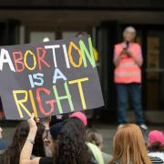 Image of a protestor holding a sign that says, "Abortion is a right"