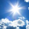 sun shining in blue sky with several clouds