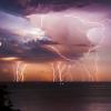 lightning striking ocean horizon at dusk