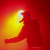hip hop performer onstage silhouetted against yellow stage light