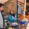 Man audio recording a woman speaking Quechua in open-air market