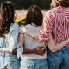 Three women shown from back with arms around each other