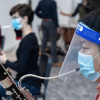 A musician playing an instrument through a faceshield