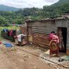 Woman carrying baby walking into corrugated metal home
