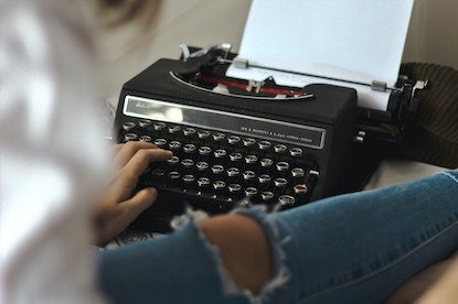 Someone typing on a black typewriter