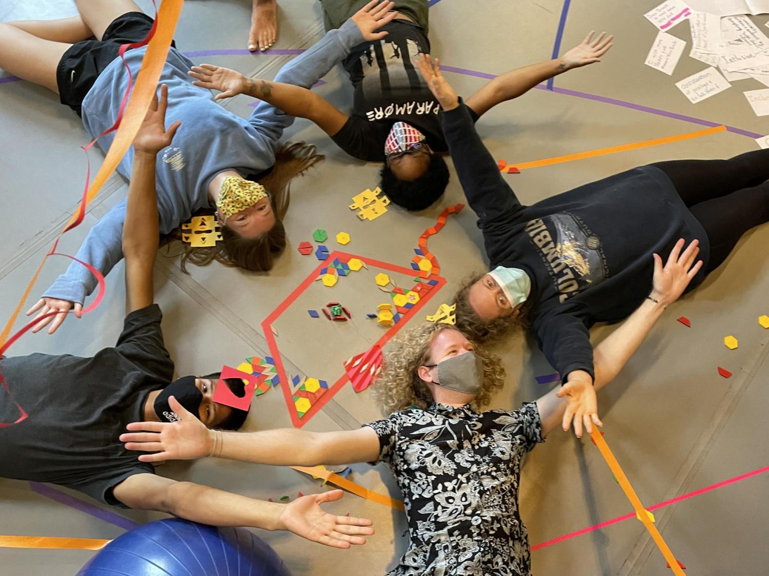 Students holding hands in a circle laying down