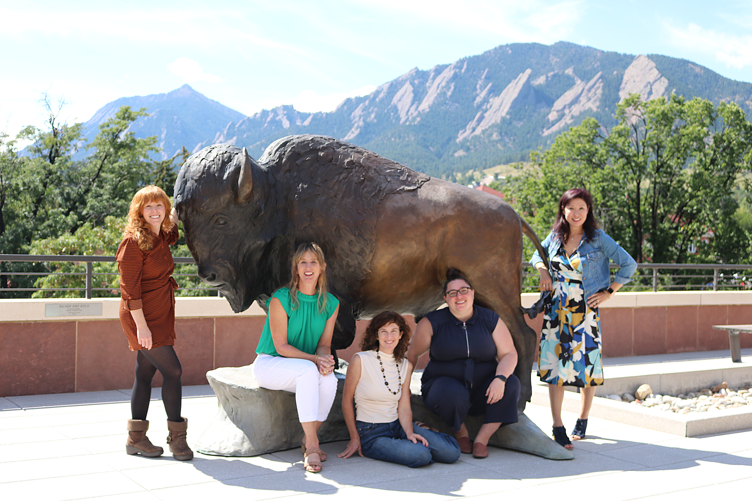 ASSETT team pose for a group photo in front of a buffalo statue with the flatirons in the background