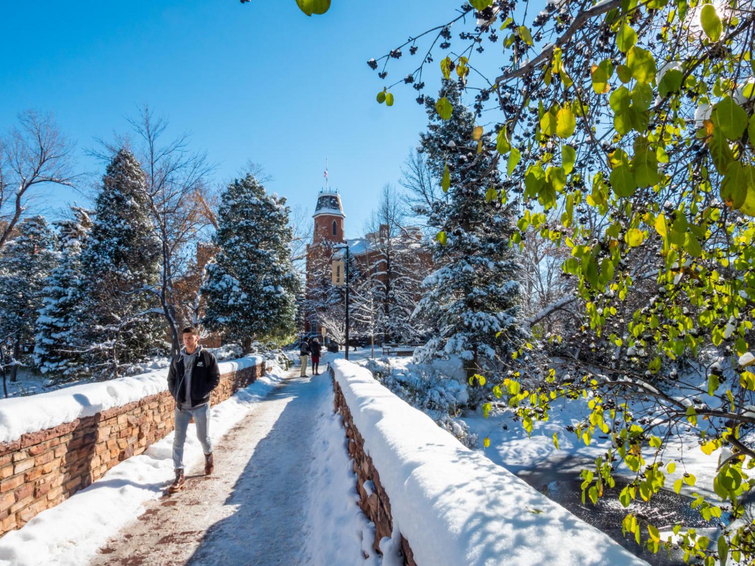 cu boulder student walking across a snowy bridge