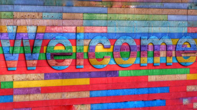 wooden backdrop with rainbow colored boards spells out the word 'welcome'