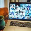 Coffee mug next to a laptop displaying participants in a Zoom meeting