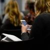 Female student using a mobile phone in a large lecture class