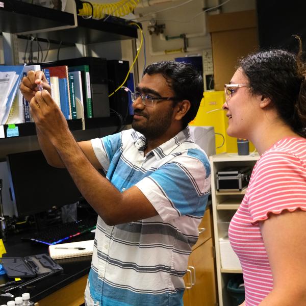 Two people examine a small plastic film together