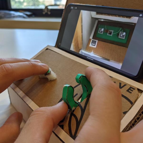 A Tinycade console with a hand gripping a "claw" controller