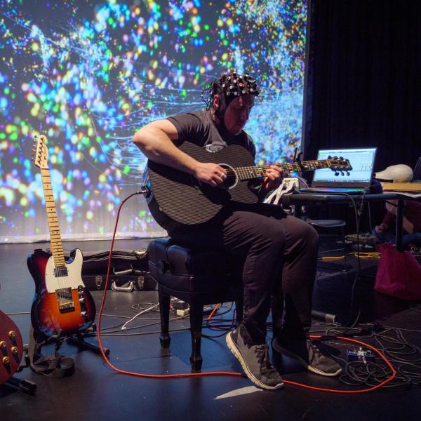 torin hopkins wearing a eeg helmet surrounded by colorful space-like projections