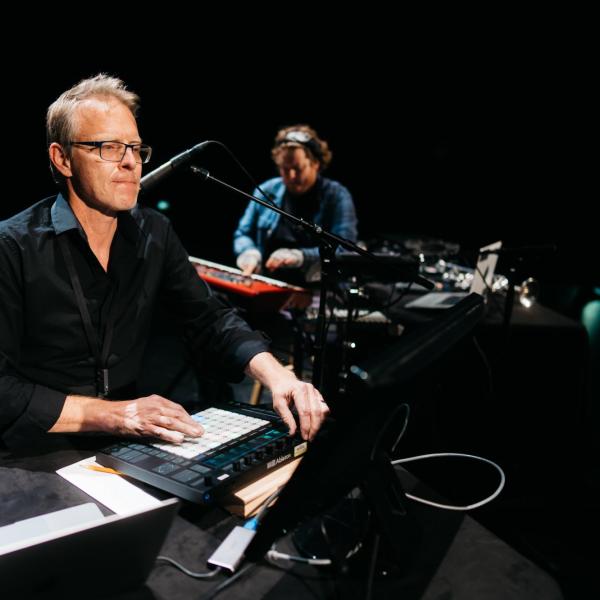 2 men playing instruments and playing with the audio