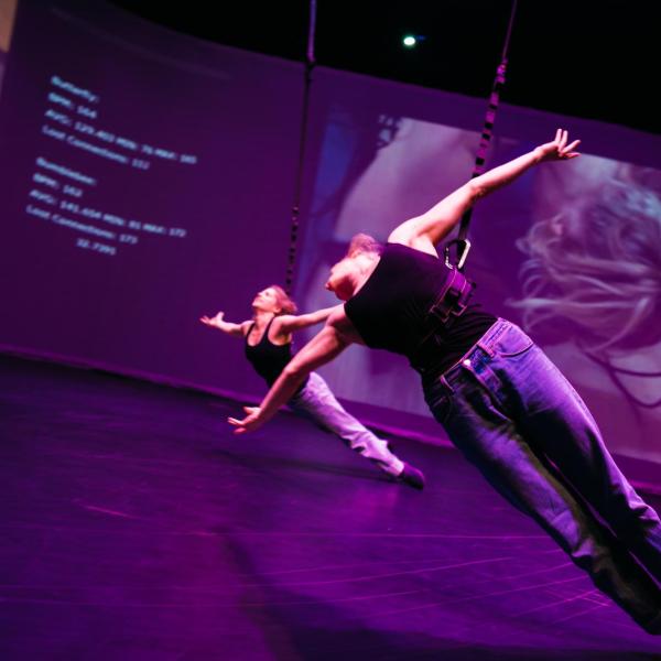two dancers in harnesses with arms wide open