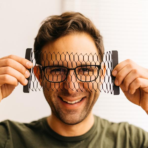 man holding paper cut outs in front of his face
