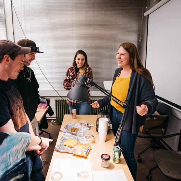 a group of masters students standing around a desk looking at plastics made of kombucha