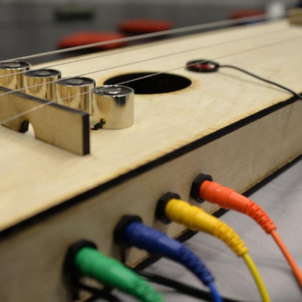 cords plugged into a fabricated instrument of wood
