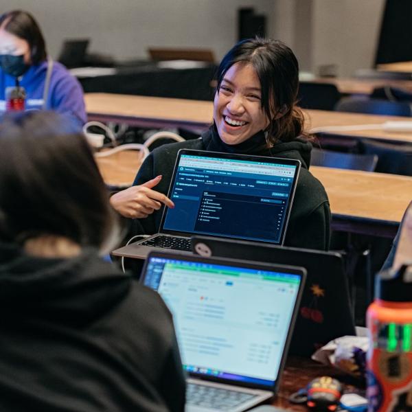laughing student attending t9Hacks pointing at code on computer screen