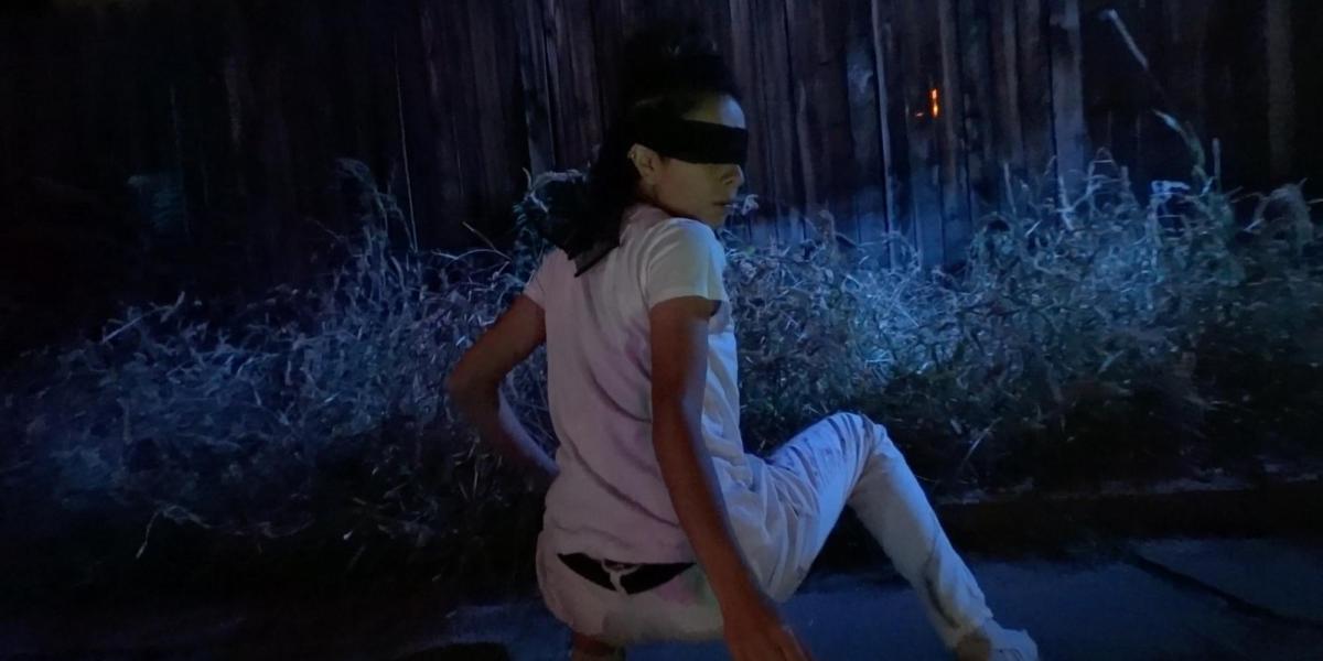 lau blind folded looking back at the camera