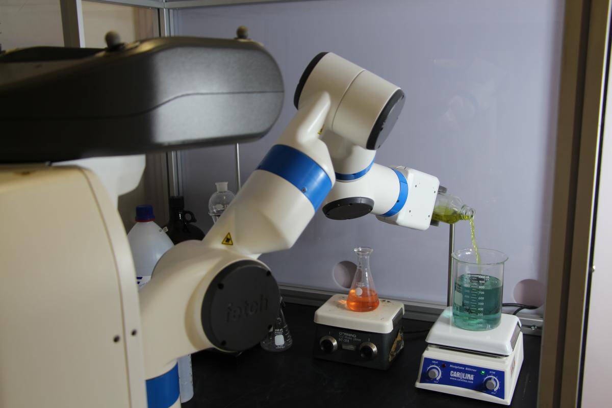 Robochemistry robotic arm pouring liquid from one beaker into another