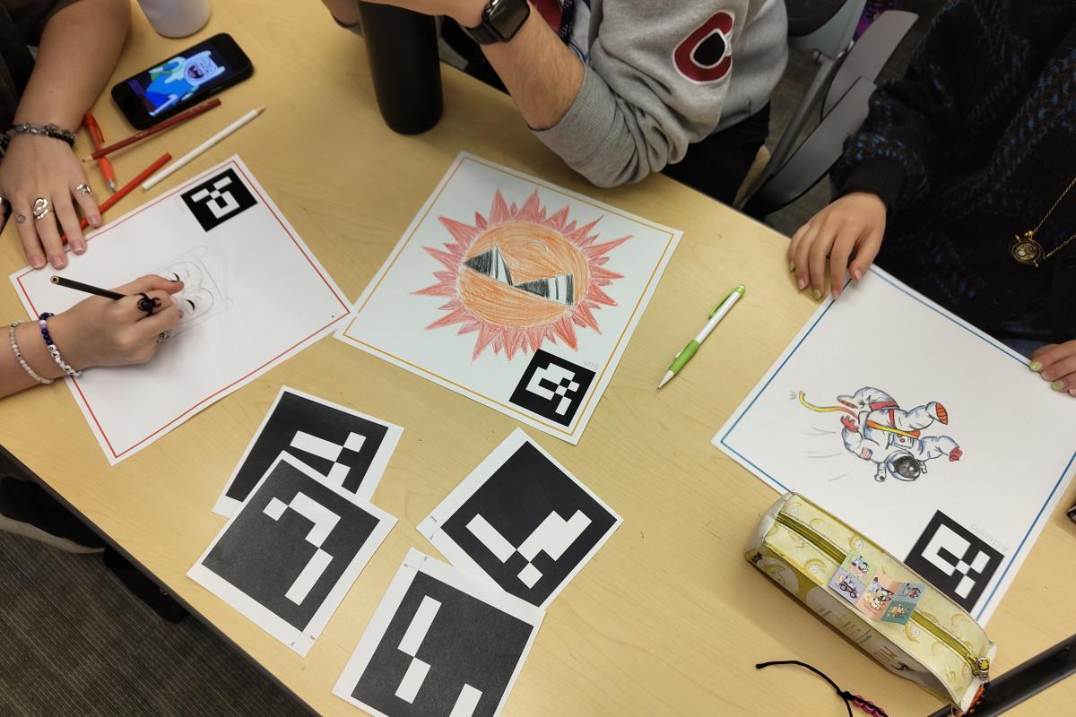 People drawing on paper seated at a table