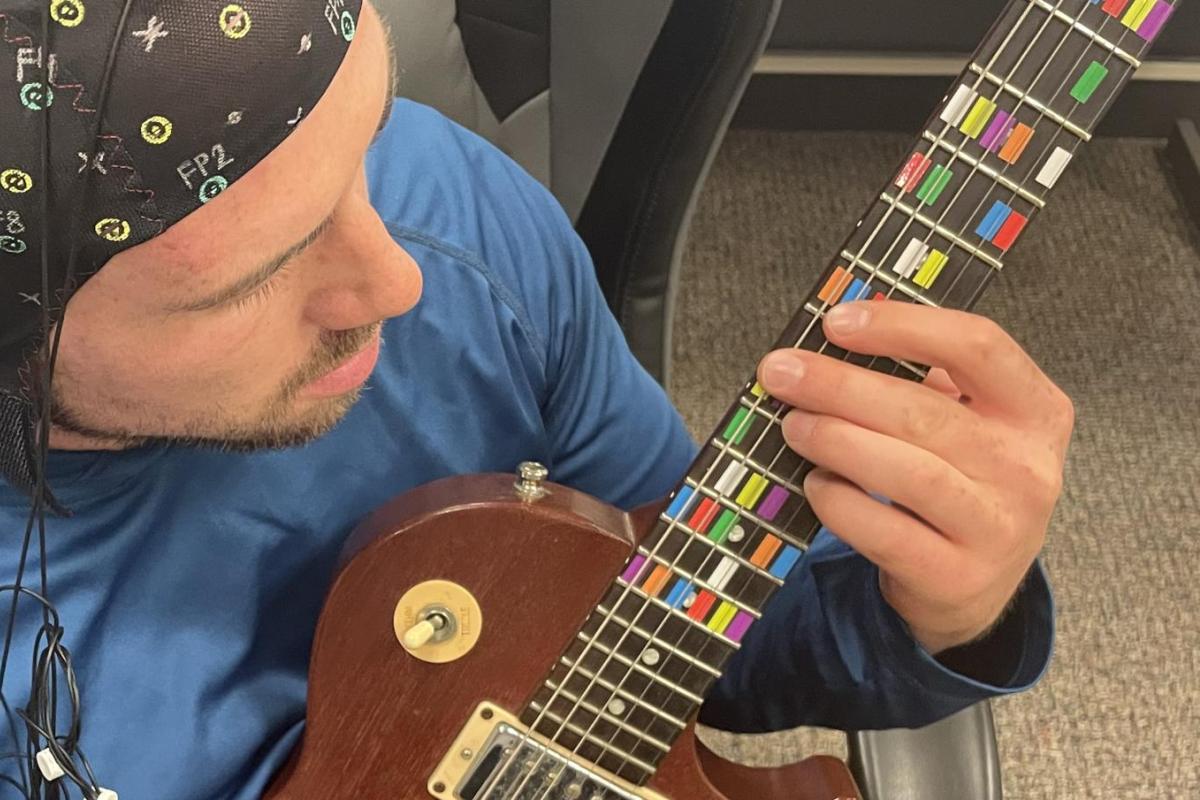 torin playing a string instrument while hooked up to a brain scanner