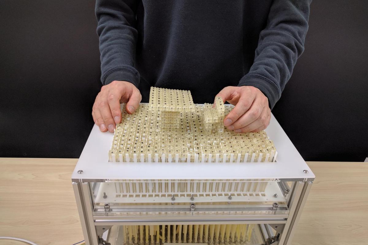 Dynablock constructs a miniature 3D model by assembling 3,000 9 mm blocks, leveraging a 24 x 16 pin-based shape display as a parallel assembler.