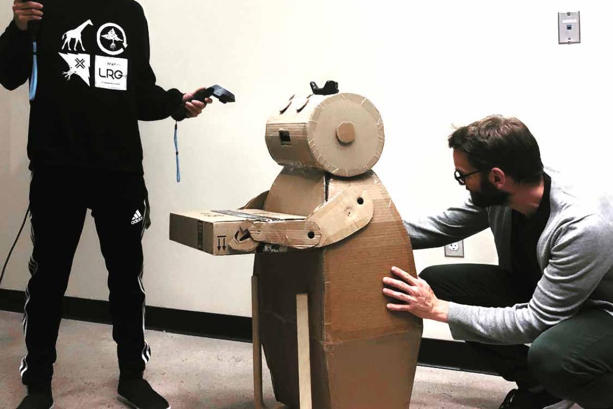 Daniel Leithinger and student working with vr headset and cardboard robot