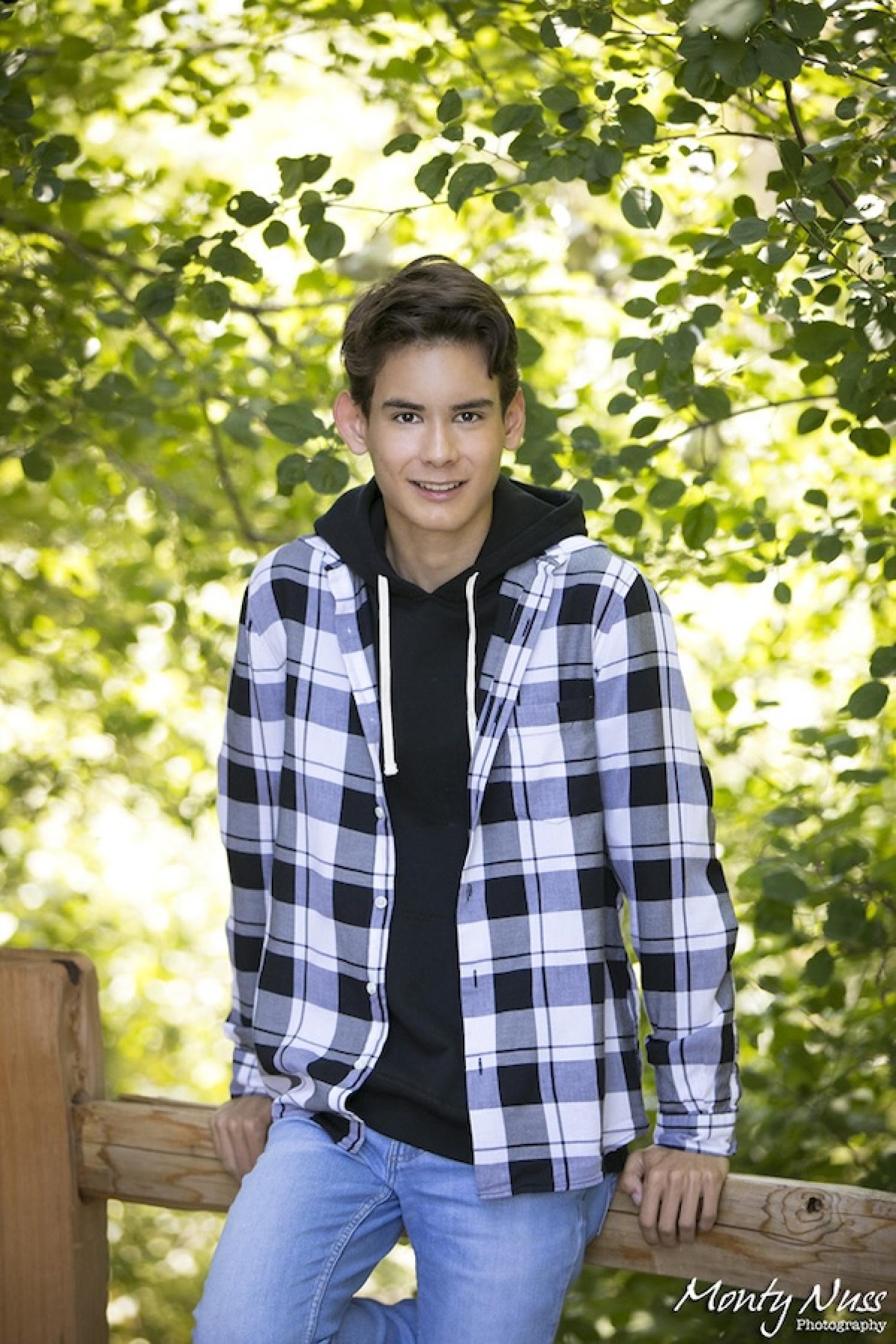 Ryan Schubert sitting on a fence with trees behind
