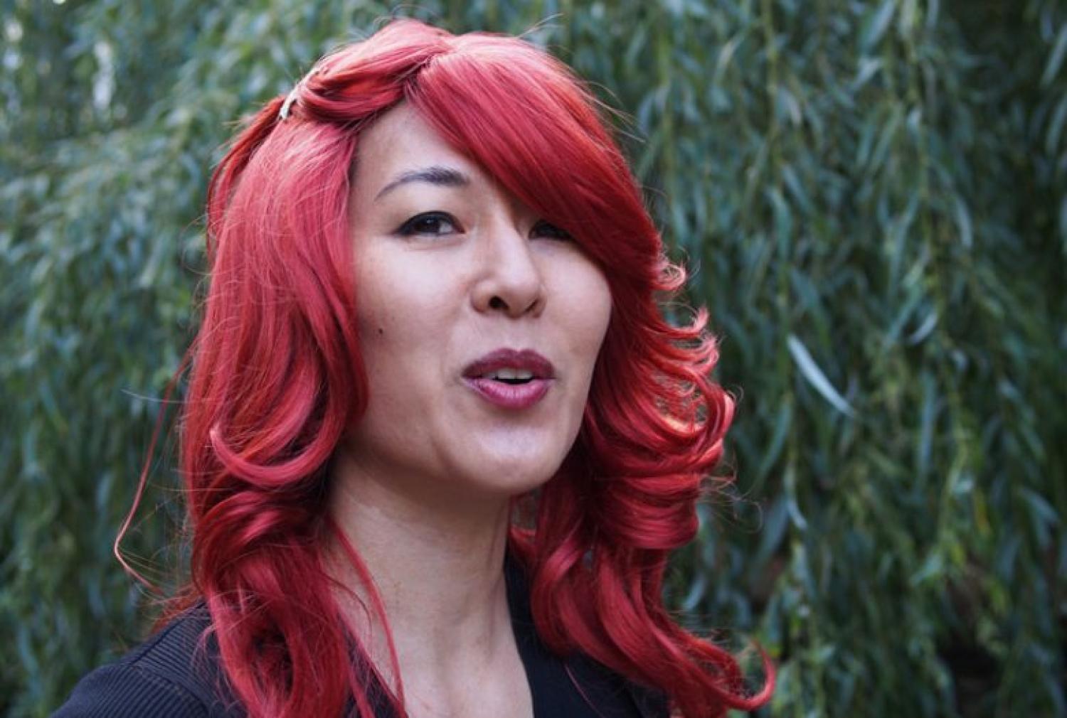 Profile of a middle-aged Asian woman with long red hair.