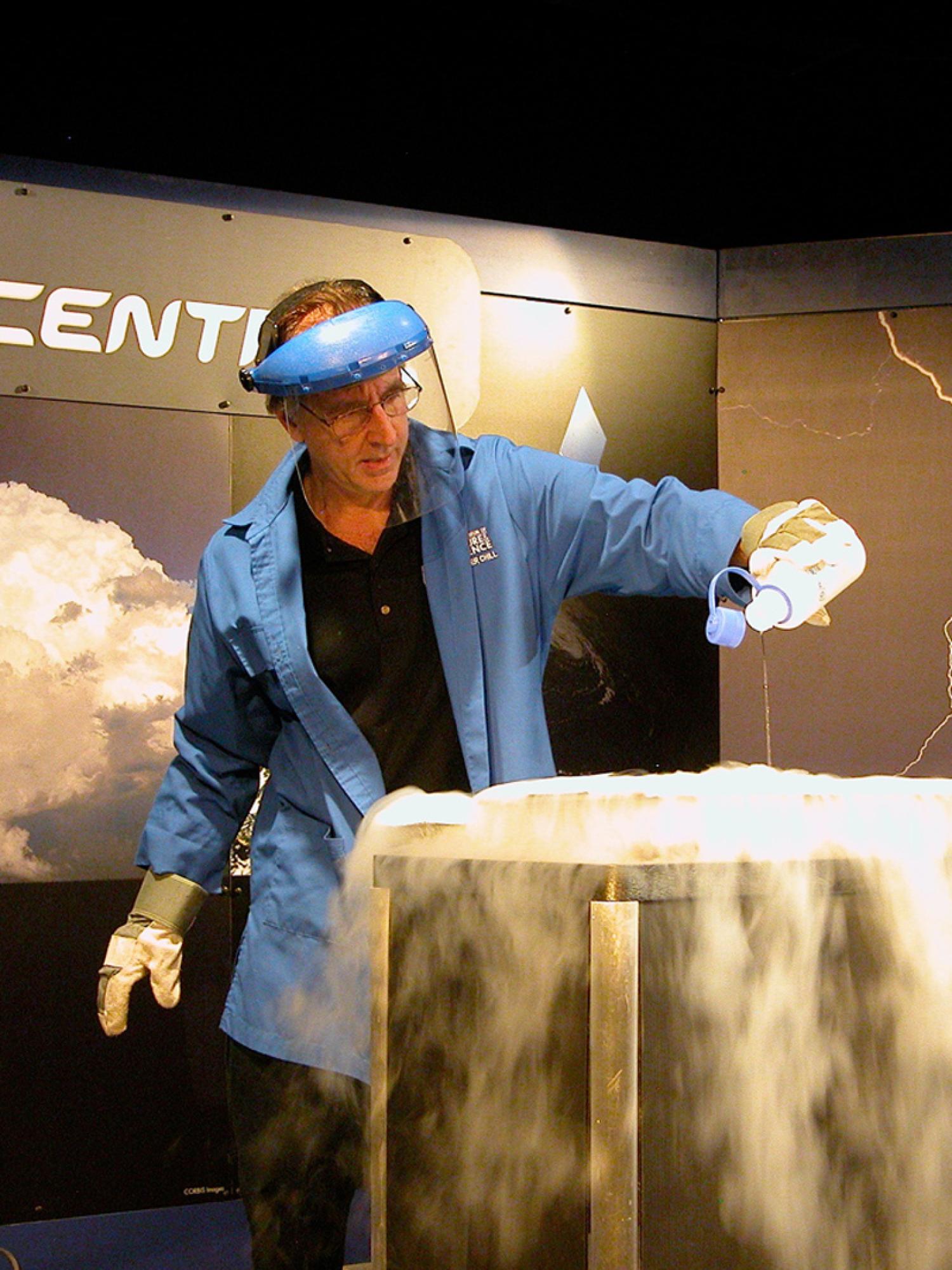 Older white man pouring a liquid into a large container, steam pouring from it.