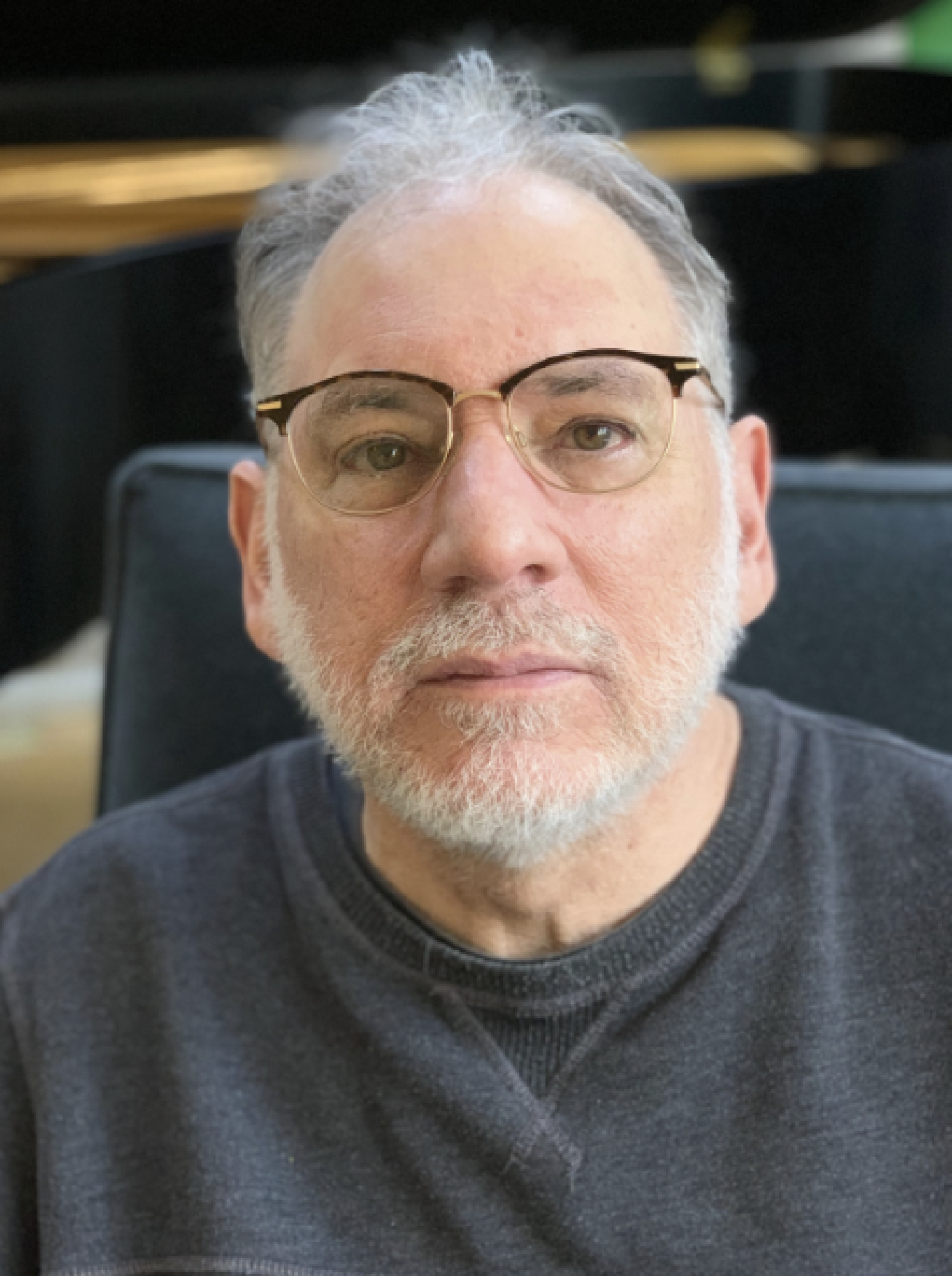 Profile of a older white man with white gray hair and a beard, wearing glasses.
