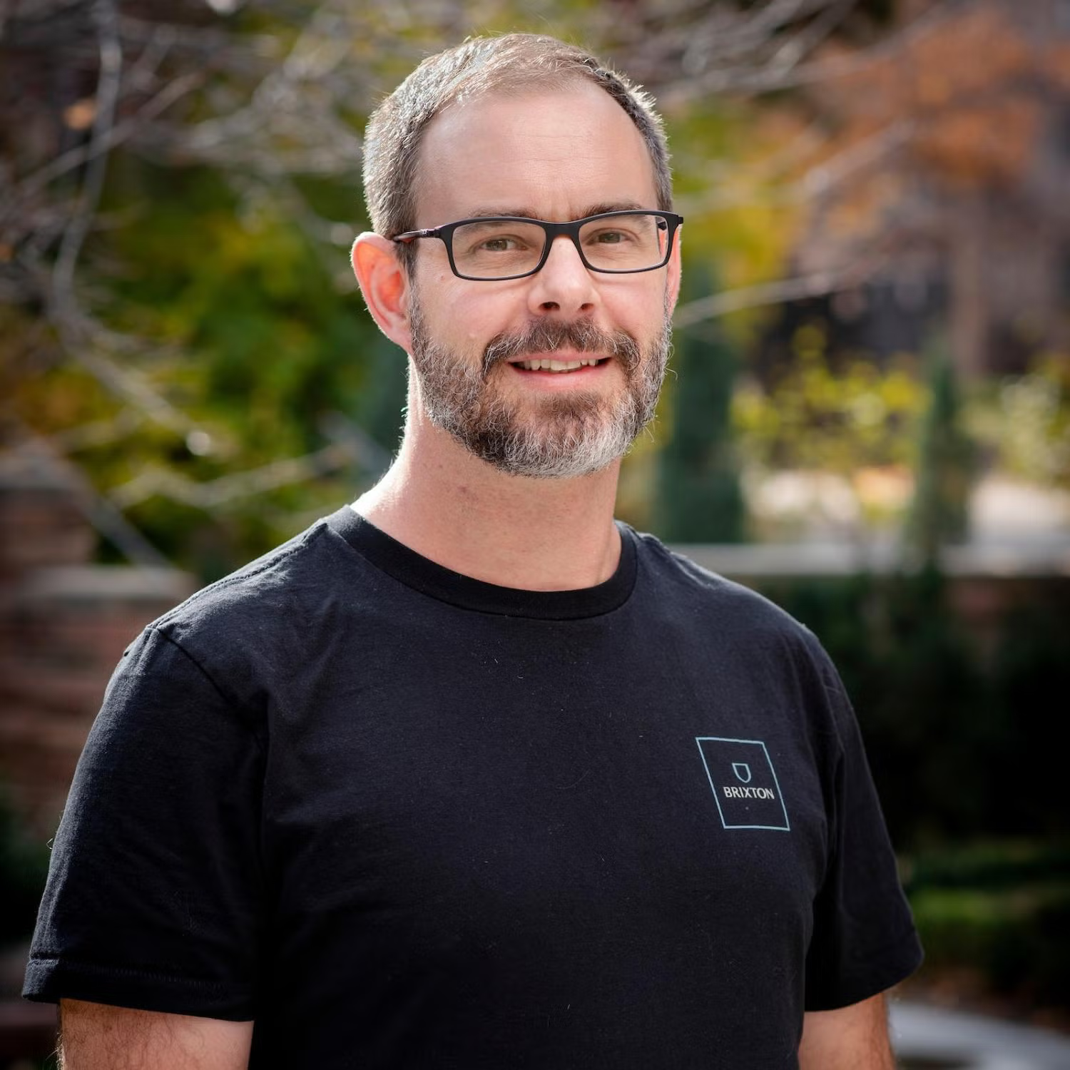 Profile of a middle-aged white man with short gray hair and a beard, wearing glasses and smiling.