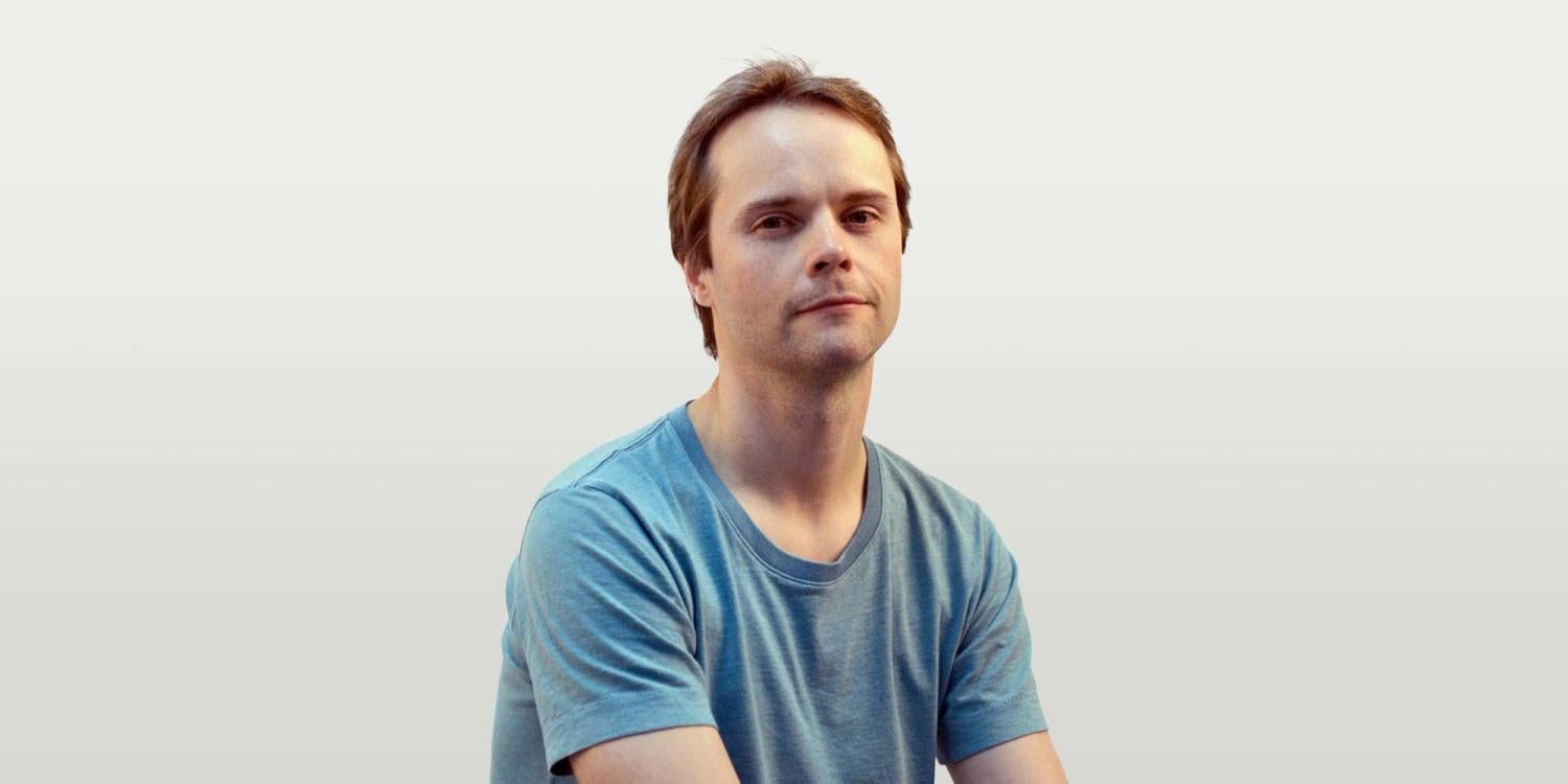 Half-body of a white man with short brown hair, wearing a blue t-shirt.