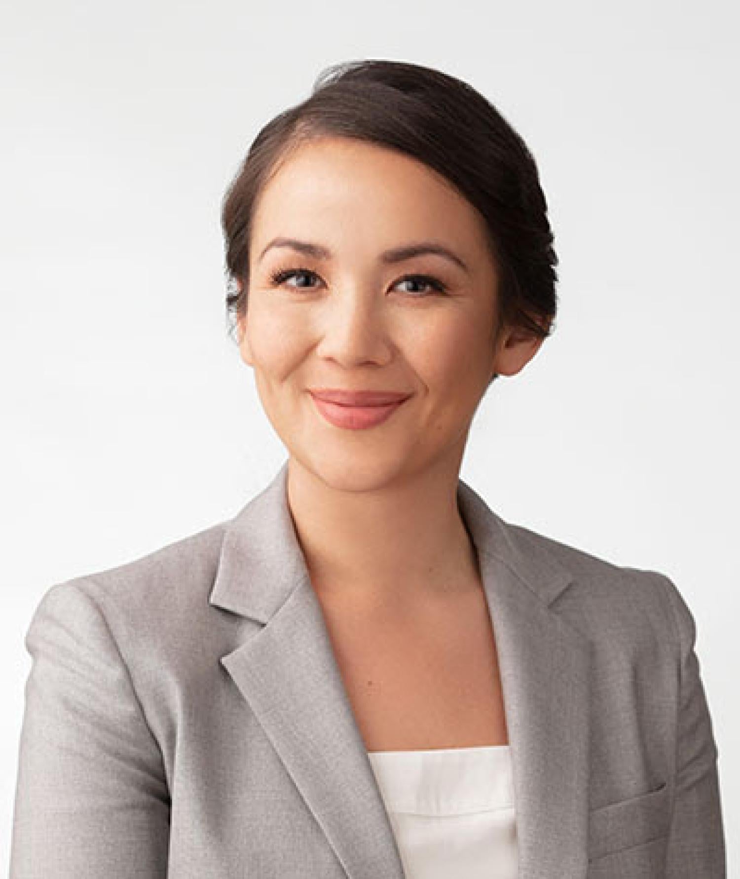 Profile image of an asian woman with tied back black hair. She is smiling and wearing a gray suit jacket.