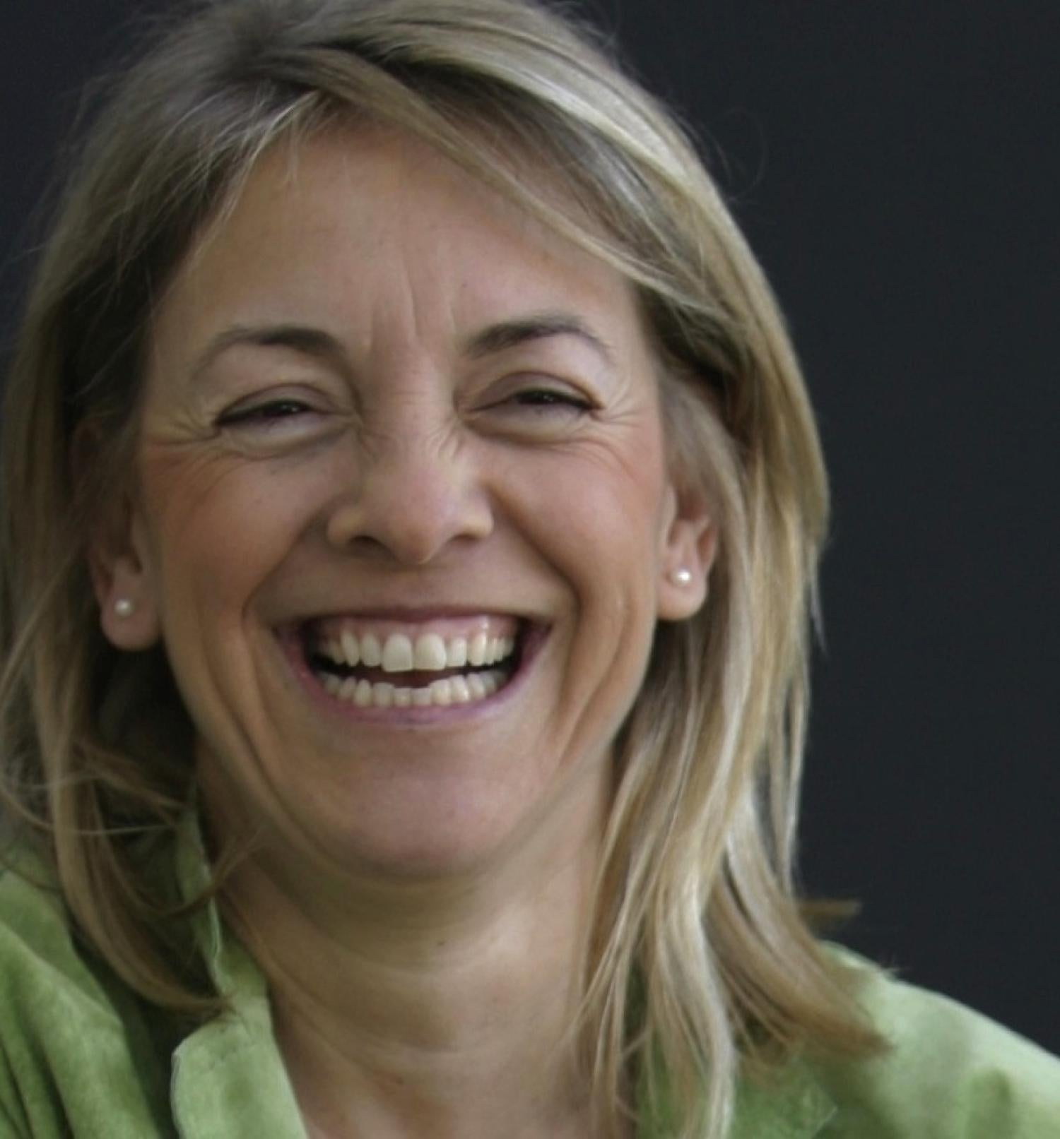 Profile of a older white woman with medium length blonde hair smiling.
