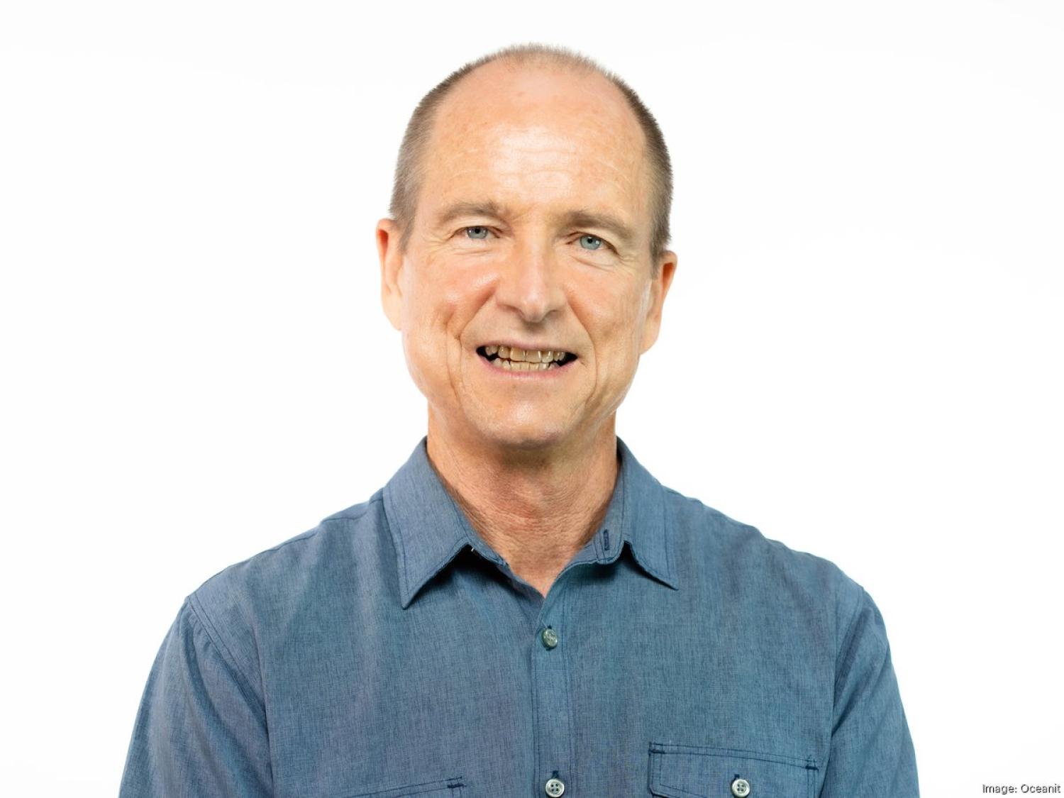 Profile of an older white man, bald, smiling.