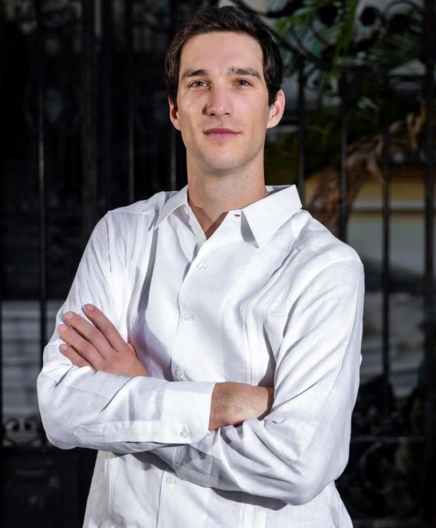 Half-body of a young white man with short dark hair, arms crossed.