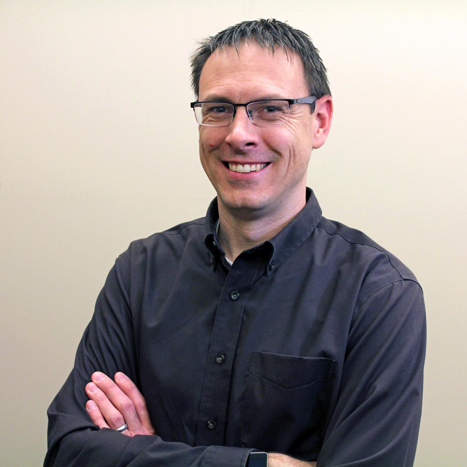Profile of a middle-aged white man with short dark hair wearing glasses.