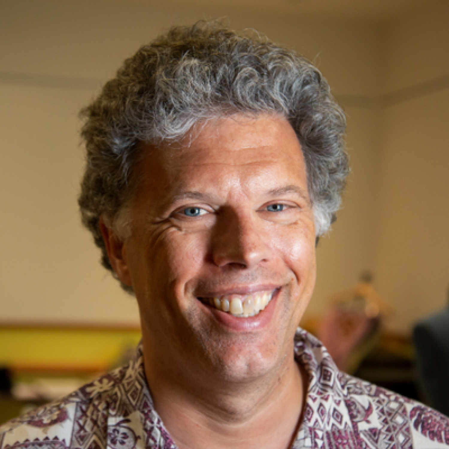 Profile image of a older brown man with short gray hair, smiling.